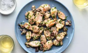 A plate of tender baby squid food, seasoned with herbs and served with a side of salt and white wine.