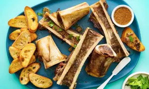 Roasted bone marrow halves served with toasted baguette slices, whole grain mustard, and parsley. A delicious bone marrow recipe.