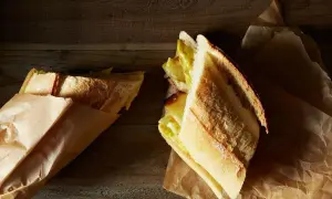 A delicious lamb bocadillo, with a golden crust and a savory filling, rests on brown paper.
