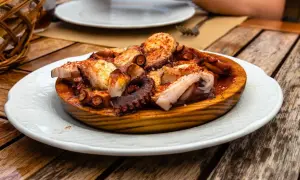 A delicious Spanish octopus dish, seasoned with paprika and served on a wooden platter on a rustic table.