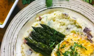 A delicious grouper recipe featuring pan-seared fish, creamy mashed potatoes with red skin, and roasted asparagus, all garnished with fresh parsley.
