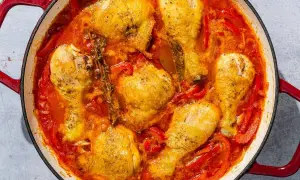 A hearty chicken basquaise simmers in a rich tomato and pepper sauce, with sprigs of thyme adding an aromatic touch.