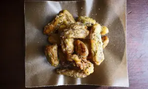Crispy, golden fried morel mushrooms, lightly salted, piled on brown parchment paper. A delicious appetizer.