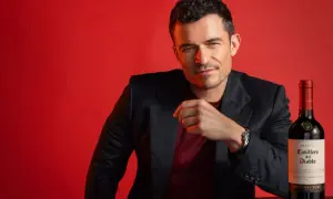 Orlando Bloom poses with a bottle of Casillero del Diablo Cabernet Sauvignon, hinting at its rich taste.