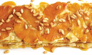 A layered dessert with caramelized pineapple slices and a creamy filling, sprinkled with toasted pine nuts. A delicious addition to pine nut recipes.
