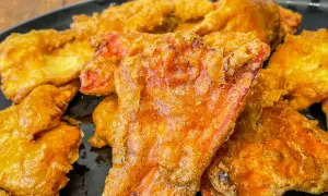 Crispy, golden-fried pieces, possibly part of a delicious chicken of the woods recipe, piled on a black plate.
