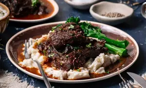 Tender beef cheek, Spanish style, served with creamy mashed potatoes and vibrant green vegetables.