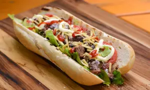 A delicious pepito sandwich overflowing with tender steak, crisp lettuce, tomato, shoestring fries, and drizzled with ketchup and mayonnaise.
