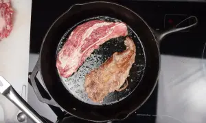 A pluma steak, a prized cut from the pork loin, sizzles in a cast-iron skillet. One side is perfectly seared, the other still raw and marbled.