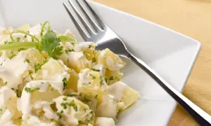 A delicious ensalada rusa española, featuring creamy potato salad with fresh herbs and a fork ready to dig in.