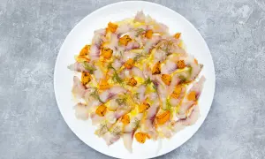 Thinly sliced sea bass crudo, glistening with olive oil and dotted with bright orange citrus segments and fresh dill.