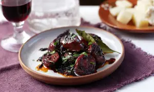 Delicious chorizo tapas, glazed and garnished with parsley, served with a glass of red wine and cheese.
