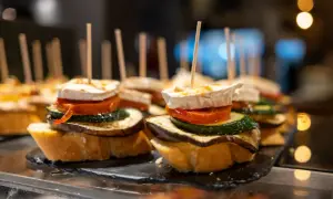 A delicious charcuterie board featuring stacked tapas on toasted bread, topped with goat cheese, tomato, zucchini, and eggplant.