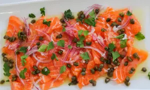 Thinly sliced salmon crudo, dressed with olive oil, capers, red onion, and parsley, is a refreshing appetizer.