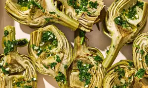 Halved artichokes, seasoned with herbs and garlic, ready for a delicious grilled artichoke recipe.