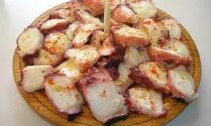 A delicious serving of pulpo a feira, tender octopus seasoned with paprika and olive oil, artfully arranged on a wooden platter.