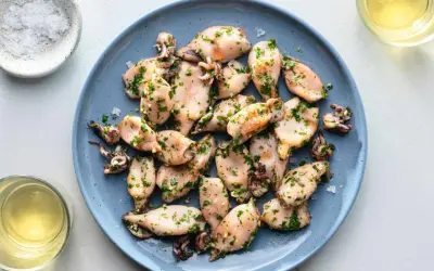 A plate of tender baby squid food, seasoned with herbs and served with a side of salt and white wine.