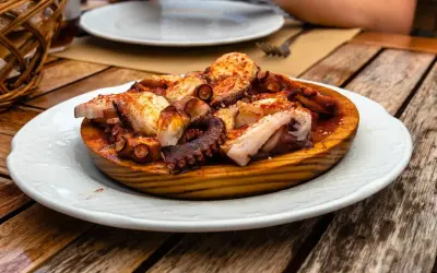 A delicious Spanish octopus dish, seasoned with paprika and served on a wooden platter on a rustic table.