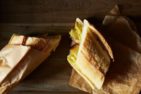 A delicious lamb bocadillo, with a golden crust and a savory filling, rests on brown paper.