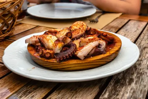 A delicious Spanish octopus dish, seasoned with paprika and served on a wooden platter on a rustic table.
