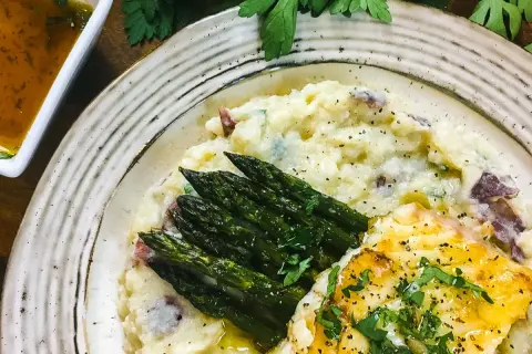 A delicious grouper recipe featuring pan-seared fish, creamy mashed potatoes with red skin, and roasted asparagus, all garnished with fresh parsley.