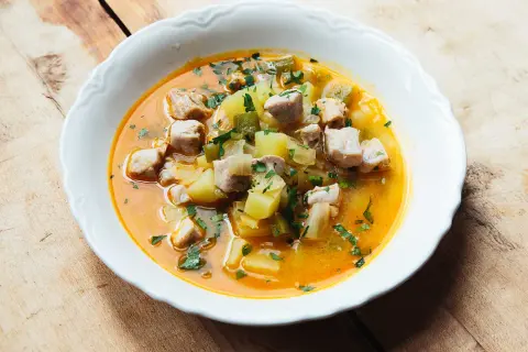 A hearty bowl of marmitako recipe, featuring tender tuna chunks, potatoes, and peppers in a rich, savory broth, garnished with fresh parsley.