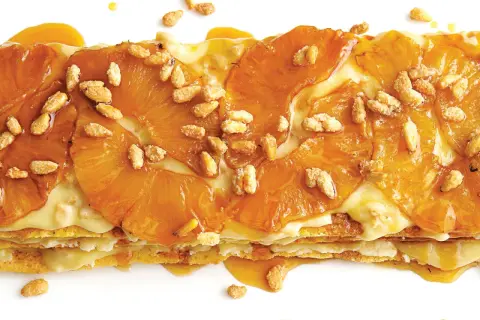 A layered dessert with caramelized pineapple slices and a creamy filling, sprinkled with toasted pine nuts. A delicious addition to pine nut recipes.