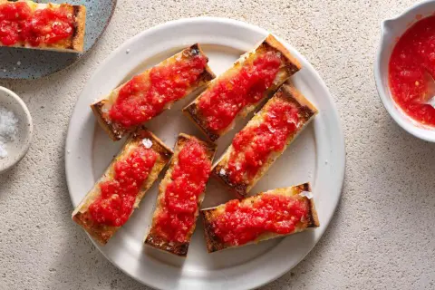 A plate of pan con tomate, toasted bread slices topped with fresh, grated tomatoes and sea salt.
