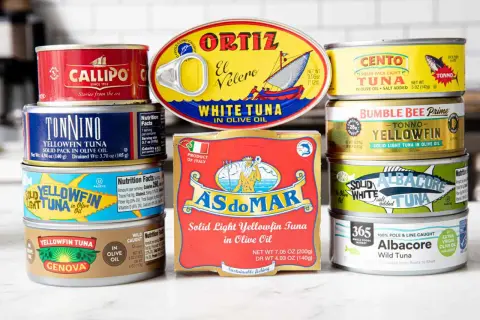 A colorful assortment of canned tuna food, featuring brands like Ortiz, Cento, Bumble Bee, and Genova, showcasing various types of tuna in olive oil.