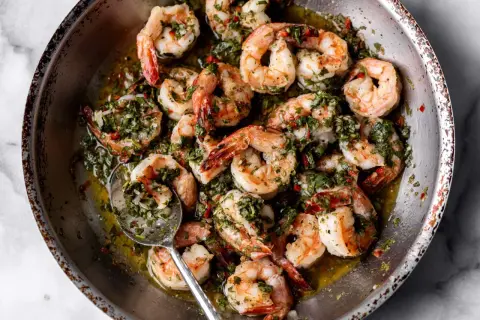 A close-up of a pan filled with succulent shrimp, glistening in a flavorful herb and garlic sauce. These are perfect for quick and delicious shrimp recipes.