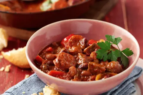A hearty bowl of Spanish beef dishes, featuring tender beef chunks, beans, and peppers in a rich, savory sauce, garnished with fresh parsley.