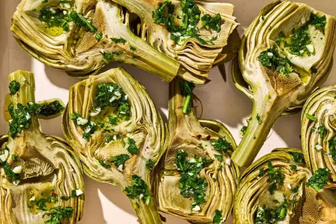Halved artichokes, seasoned with herbs and garlic, ready for a delicious grilled artichoke recipe.