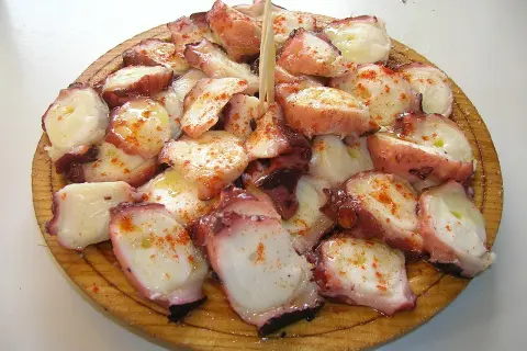 A delicious serving of pulpo a feira, tender octopus seasoned with paprika and olive oil, artfully arranged on a wooden platter.