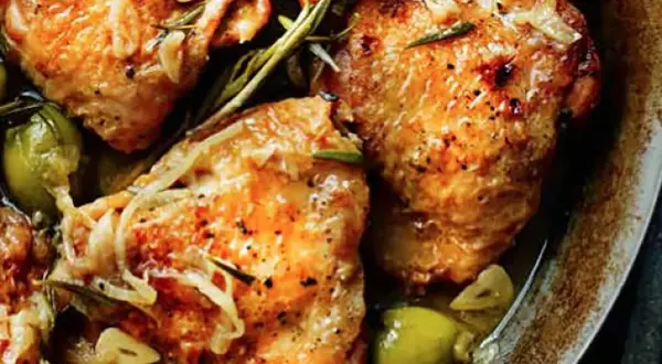 Juicy chicken tapa with olives, garlic, and rosemary, seasoned with pepper and herbs, served in a rustic dish.