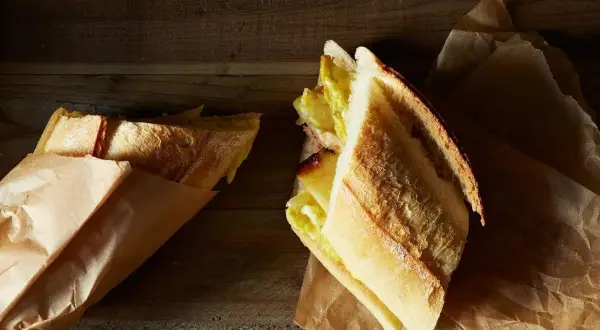 A delicious lamb bocadillo, with a golden crust and a savory filling, rests on brown paper.
