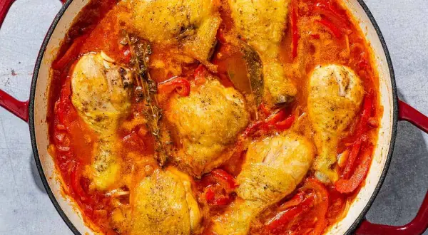 A hearty chicken basquaise simmers in a rich tomato and pepper sauce, with sprigs of thyme adding an aromatic touch.