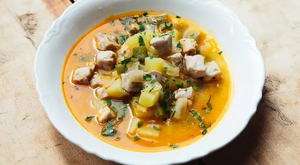 A hearty bowl of marmitako recipe, featuring tender tuna chunks, potatoes, and peppers in a rich, savory broth, garnished with fresh parsley.