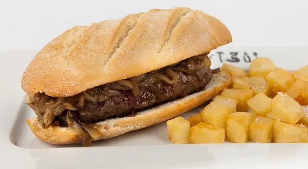 A pepito, a delicious steak sandwich with caramelized onions, served with crispy fried potatoes.