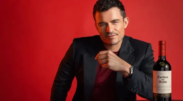Orlando Bloom poses with a bottle of Casillero del Diablo Cabernet Sauvignon, hinting at its rich taste.
