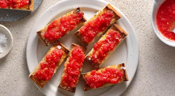A plate of pan con tomate, toasted bread slices topped with fresh, grated tomatoes and sea salt.