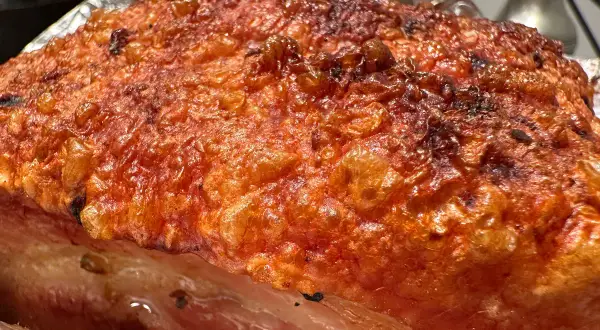 Crispy, golden-brown crackling on a succulent Iberico pork belly recipe, ready to be carved.