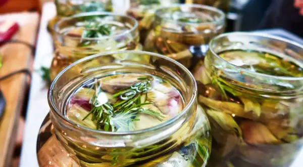 Jars filled with pickled artichoke hearts and rosemary sprigs, ready for a delicious meal.