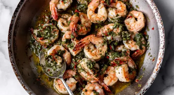 A close-up of a pan filled with succulent shrimp, glistening in a flavorful herb and garlic sauce. These are perfect for quick and delicious shrimp recipes.
