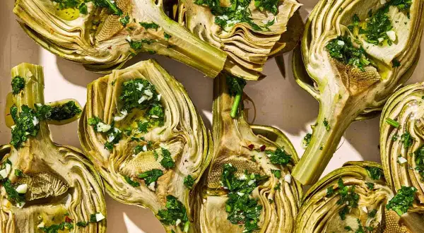 Halved artichokes, seasoned with herbs and garlic, ready for a delicious grilled artichoke recipe.