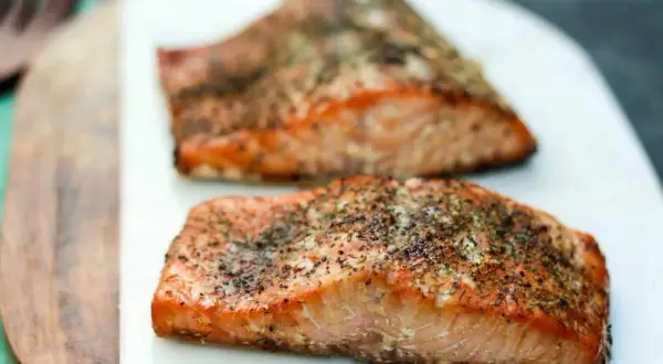 Two seasoned salmon fillets, ready to be smoked. Learn how to smoke salmon in an electric smoker for a delicious meal.
