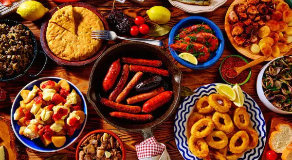 A vibrant spread of Spanish tapas: fried calamari, grilled sardines, chorizo, patatas bravas, and more. These small plates are perfect for sharing!