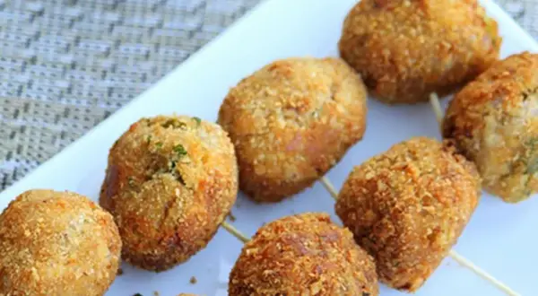 Golden-brown tuna balls on skewers, coated in crispy breadcrumbs, are arranged on a white platter.