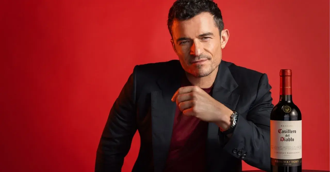 Orlando Bloom poses with a bottle of Casillero del Diablo Cabernet Sauvignon, hinting at its rich taste.
