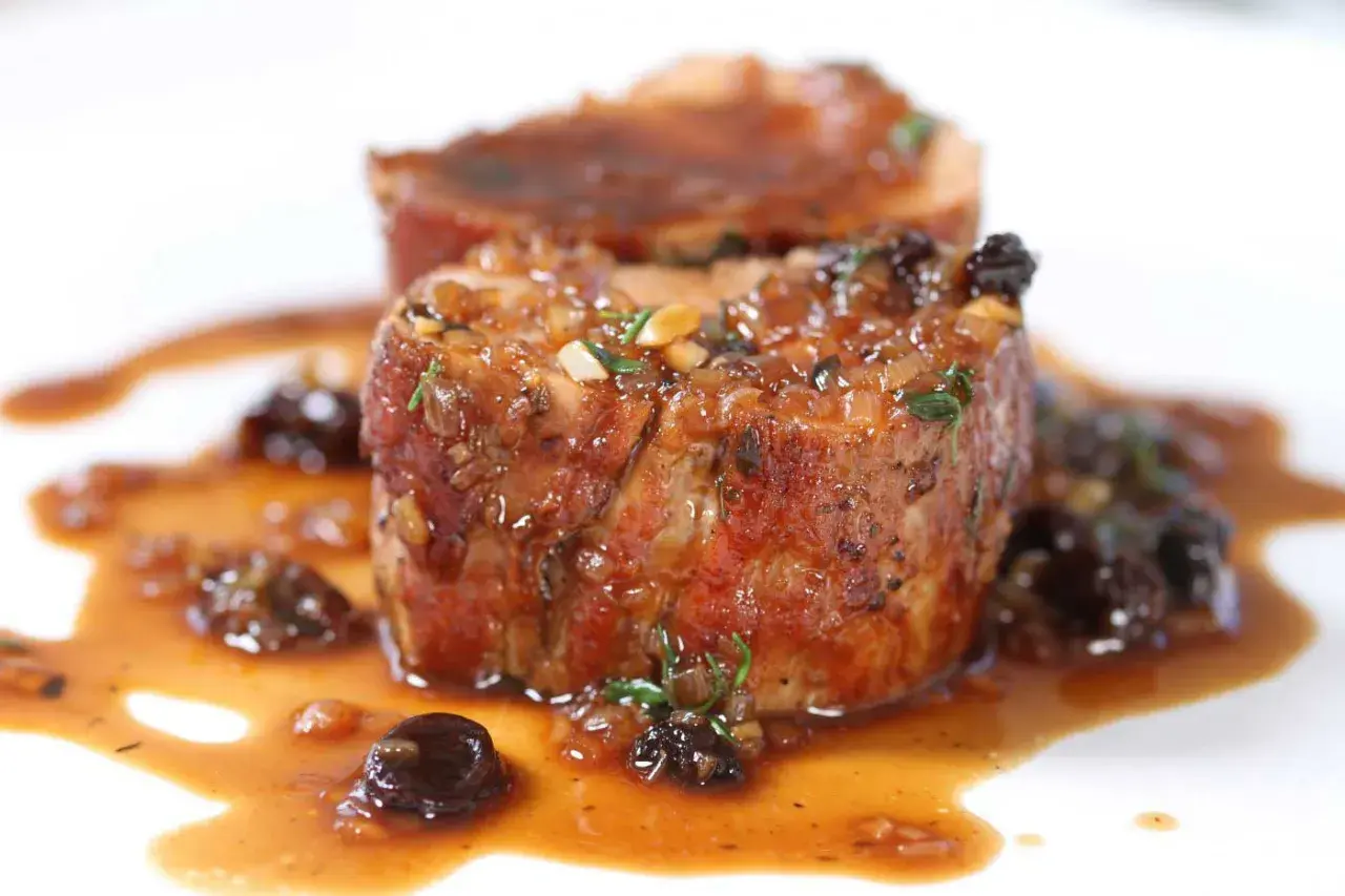 Succulent Iberico pork shoulder recipe, seared and glazed with a rich sauce and studded with dried fruit.
