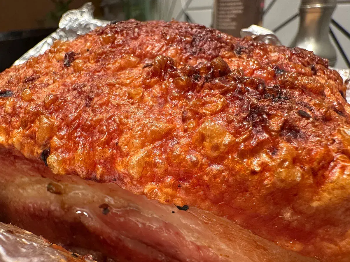 Crispy, golden-brown crackling on a succulent Iberico pork belly recipe, ready to be carved.